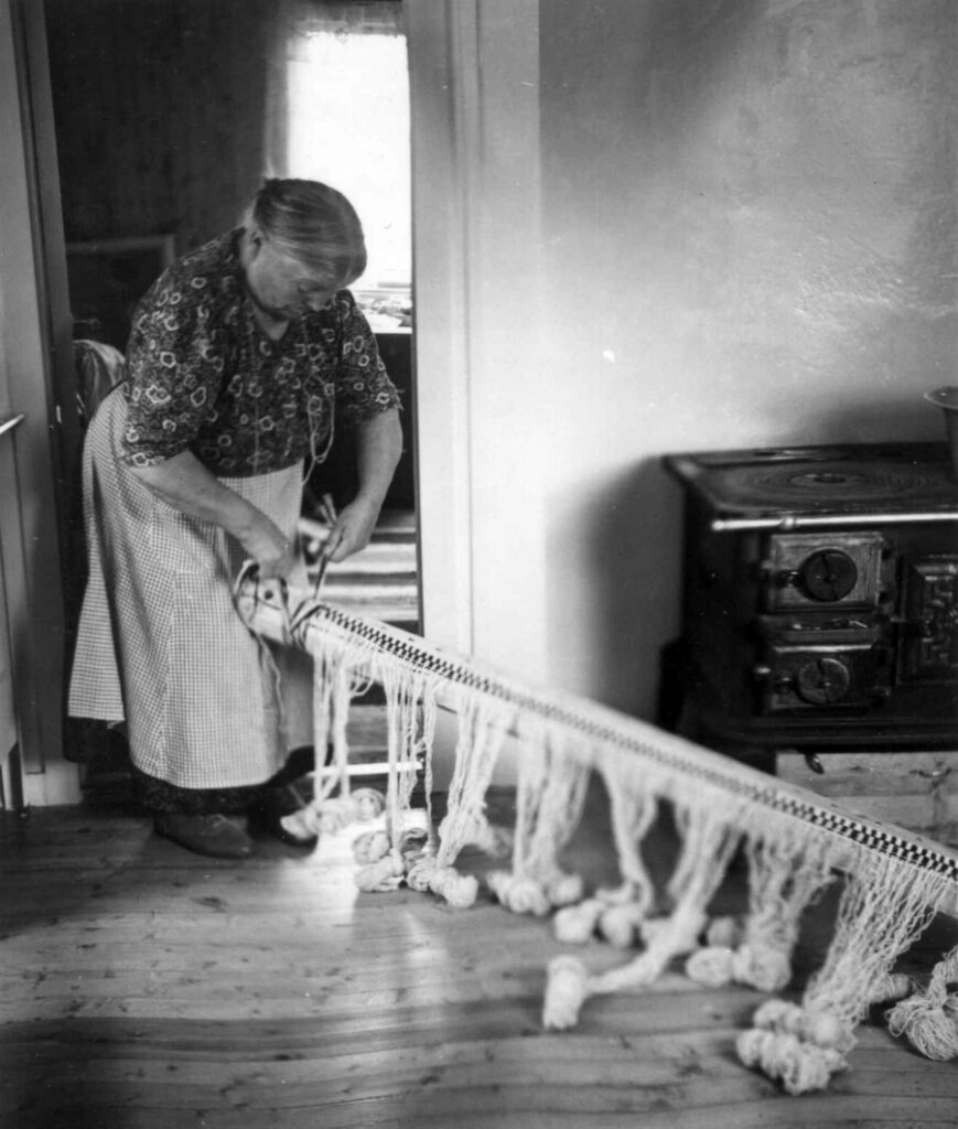 Anne Hansen knytter grenteppets renning til bommen. 