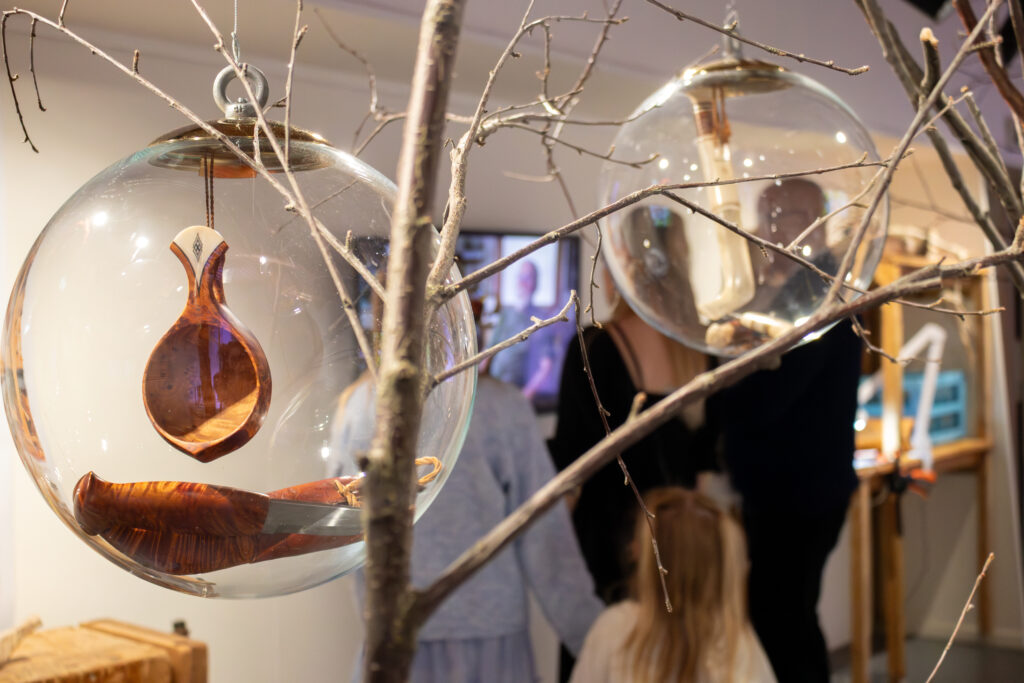 Decorative glass orbs with wooden inner shapes hanging from bare branches in a shop display.